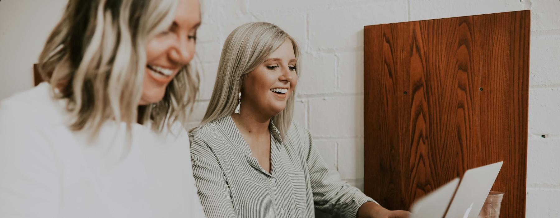 a couple of women looking at a laptop