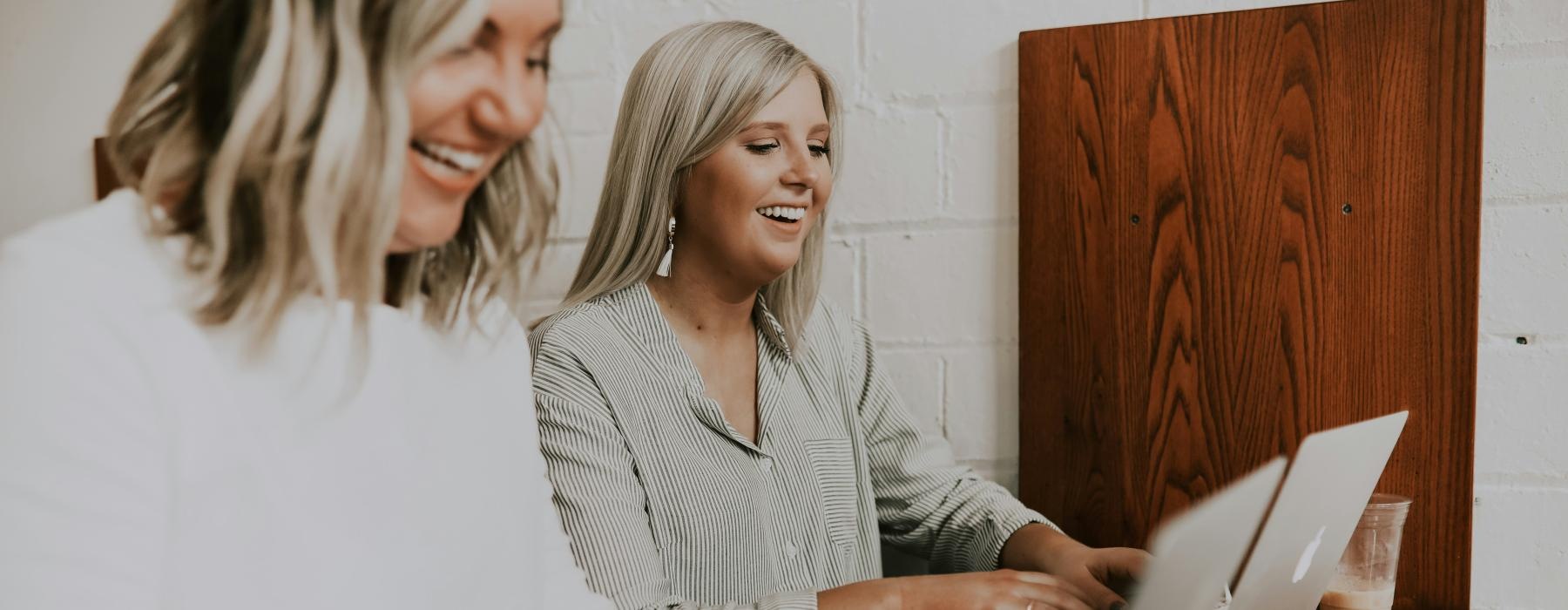 a couple of women looking at a laptop